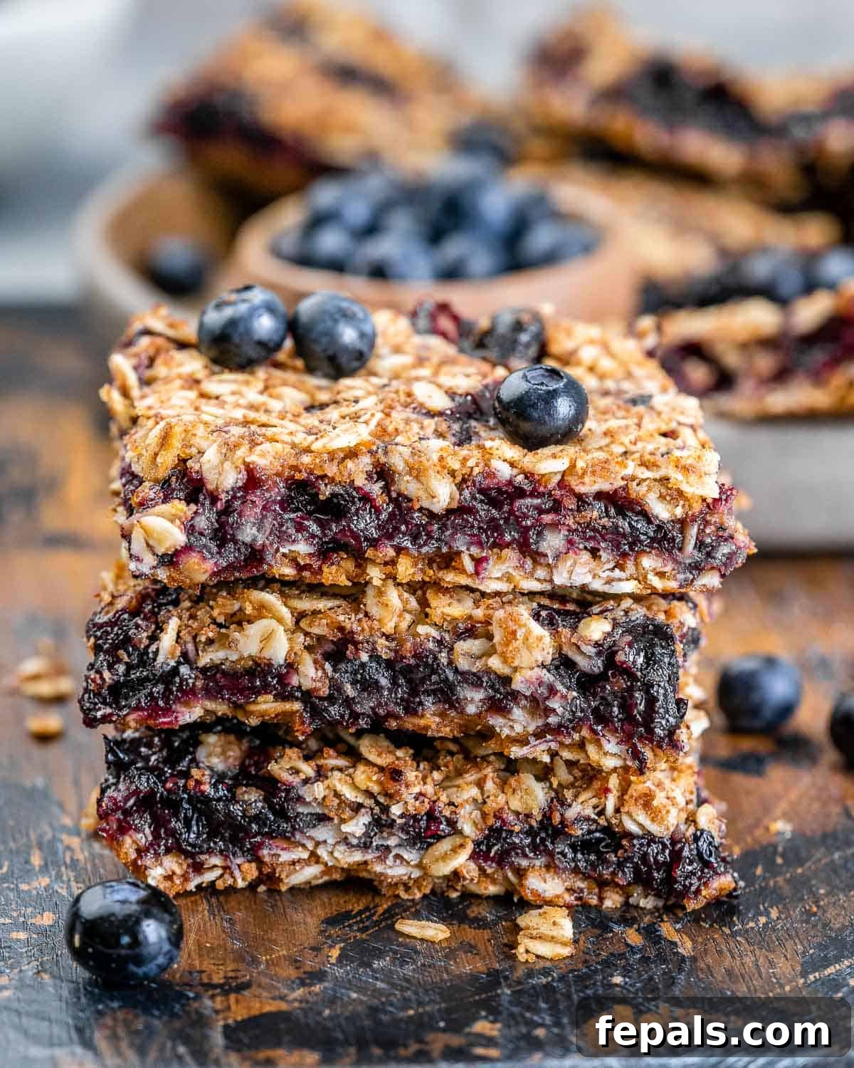 3 oatmeal bars stacked over each other on a cutting board.