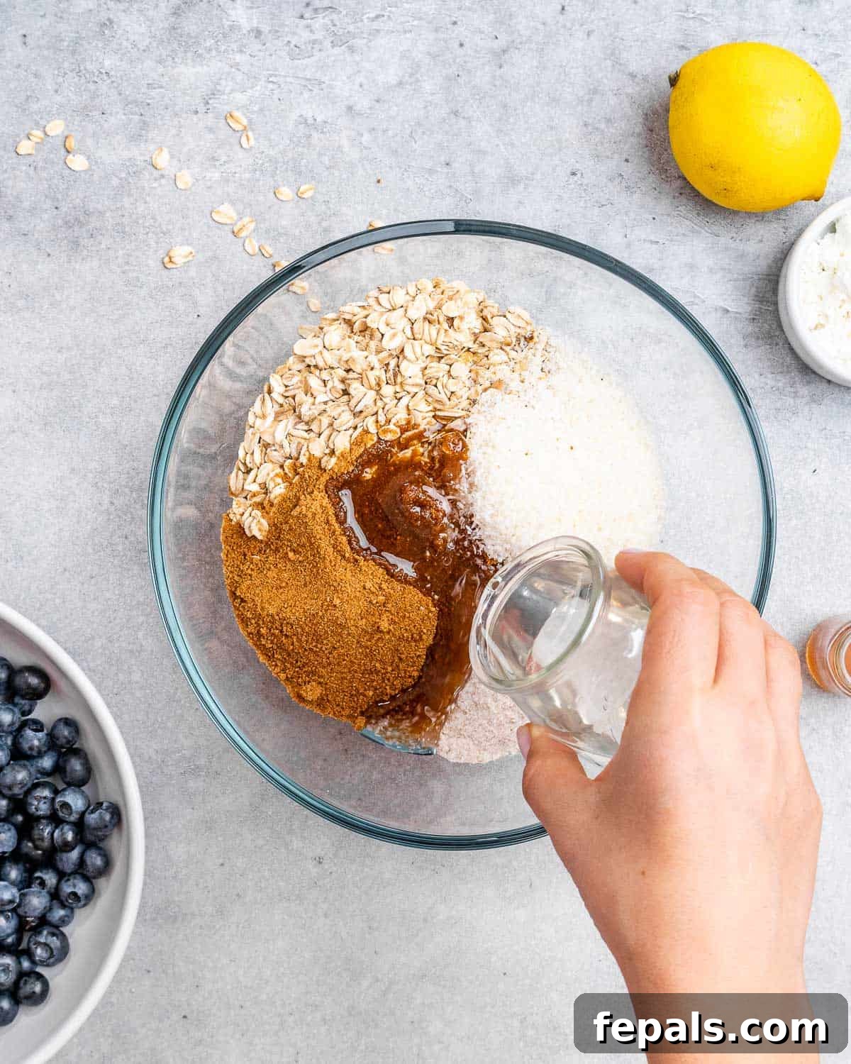 coconut oil added into a bowl with flour, rolled oat, shredded coconut, and coconut sugar.