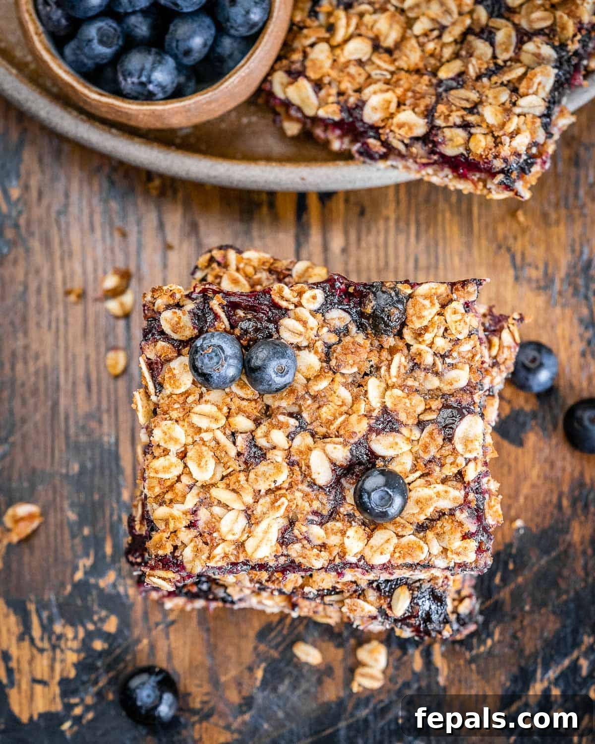 blueberry bars stacked over each other on a brown wooden surface.