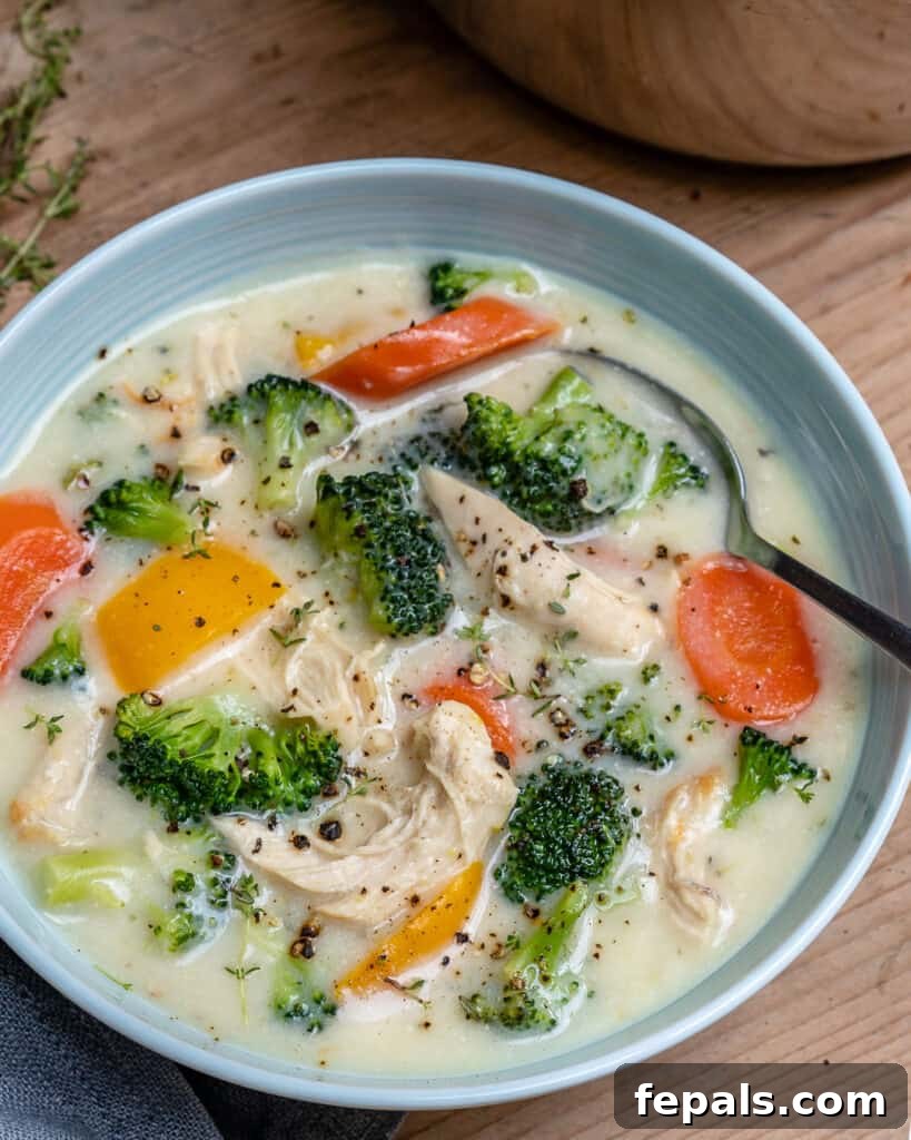 Velvety Chicken and Broccoli Potage 6 side shot of a white bowl of creamy chicken soup with broccoli and carrits