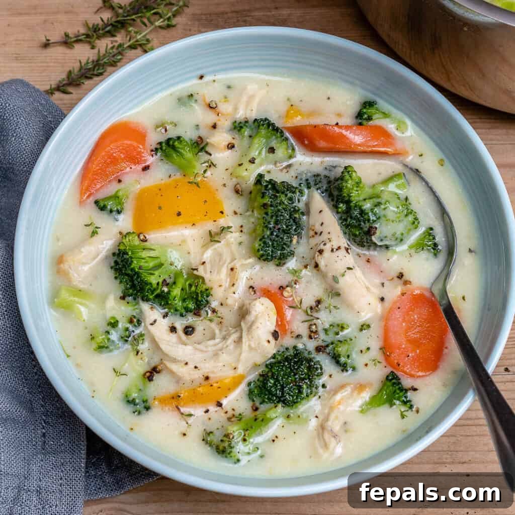 Velvety Chicken and Broccoli Potage 7 top view os a white bowl of creamy white looking chicken soup with broccoli, yellow peppers, and carrots