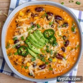 Southwest Creamy Chicken Enchilada Soup 11 chicken enchilada soup in a round white bowl topped with shredded cheese and sliced avcoado.