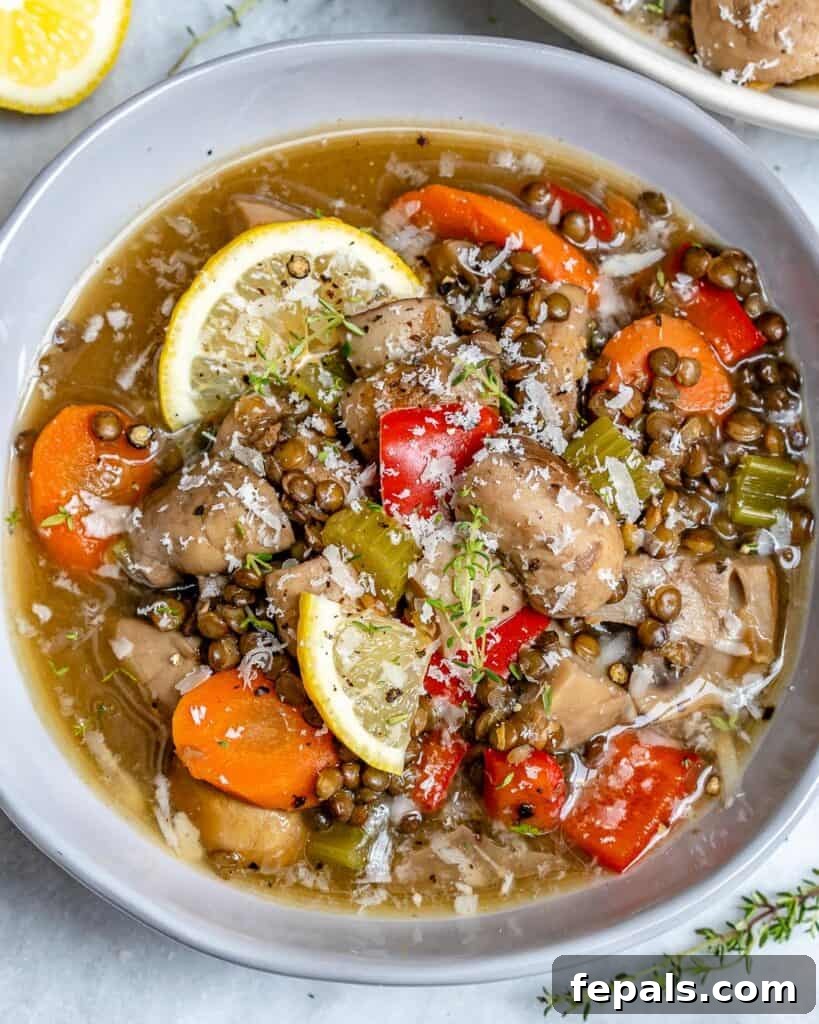 top view of crockpot lentil soup with mushrooms and  carrots with lemon garnish