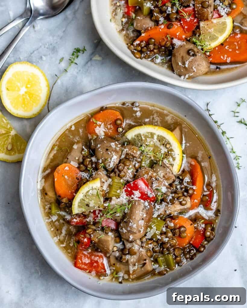 top view of a bowl with lentil and mushroom soup with lemon garnish