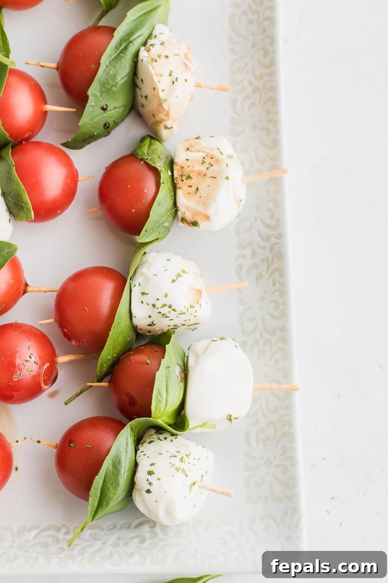 Delicious and easy Caprese skewers with fresh cherry tomatoes, mozzarella balls, and basil leaves