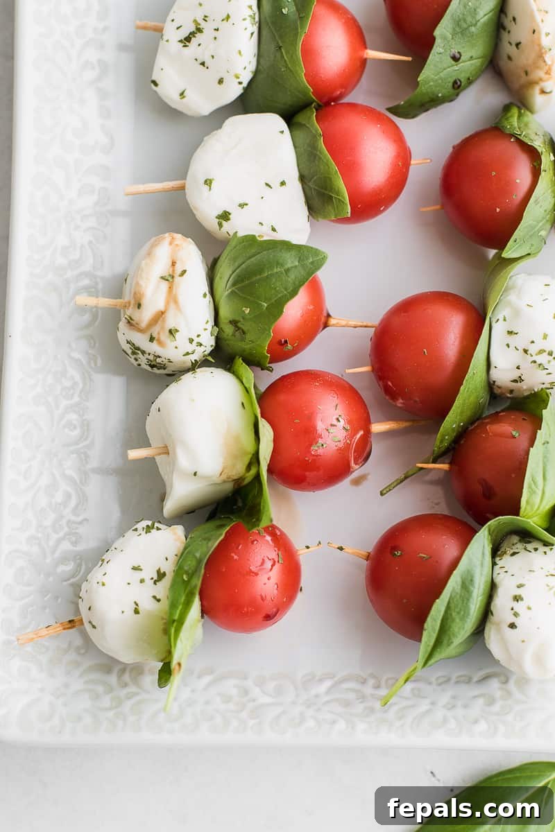 Close-up of a Caprese skewer showcasing vibrant cherry tomatoes, fresh basil, and creamy mozzarella balls