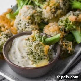Crispy cheesy baked broccoli floret in a white dipping sauce.