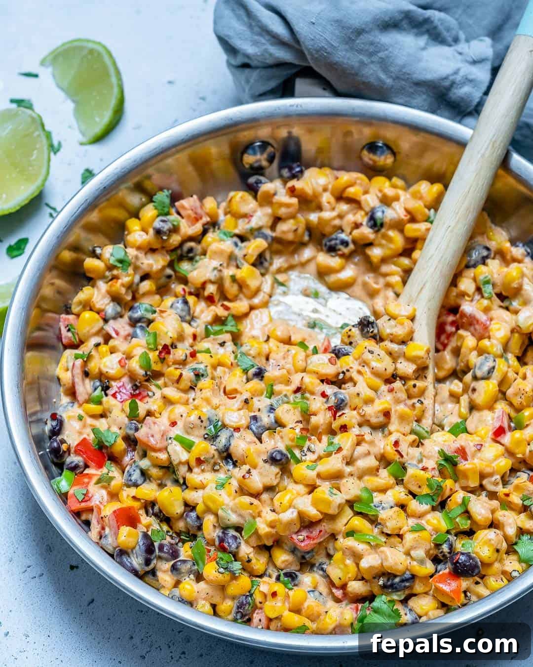 Easy to make street corn salad recipe A large serving of creamy Mexican street corn salad with a spoon, highlighting its texture and fresh ingredients.