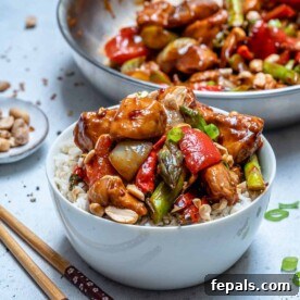 side shot of a white bowl with kung pao chicken served over rice