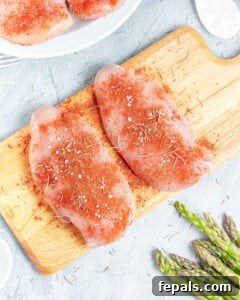Chicken breasts seasoned with seasonings on a cutting board.