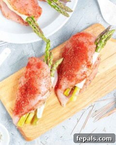 chicken breasts stuffed chicken asparagus, cheese, and sun-dried tomatoes on a cutting board. Before baking.