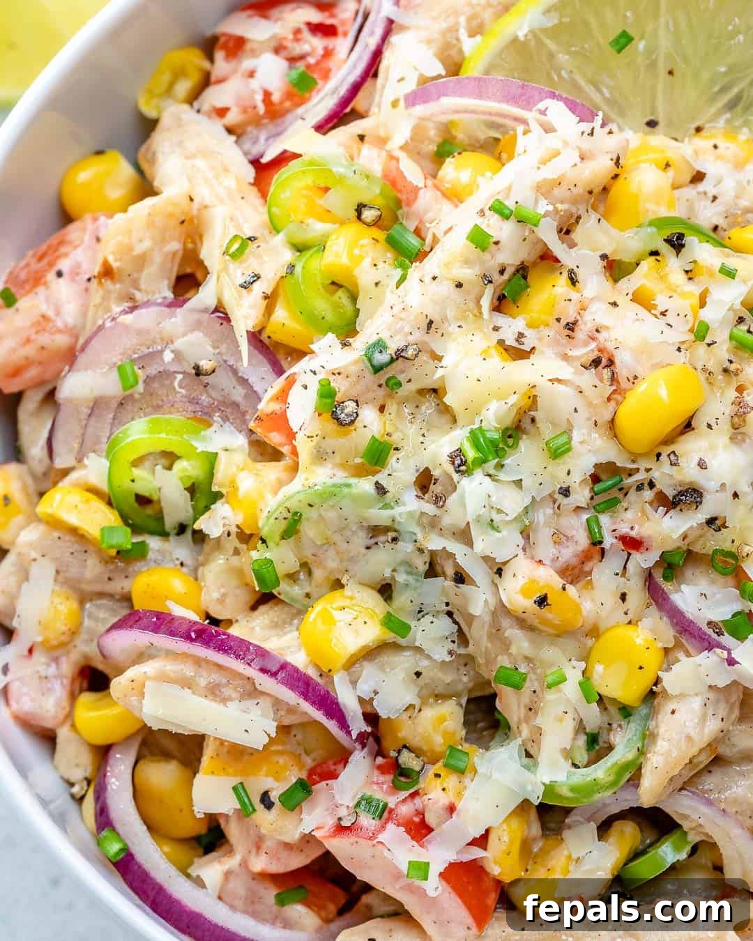 pasta salad in a bowl with shredded cheese and lime wedge.