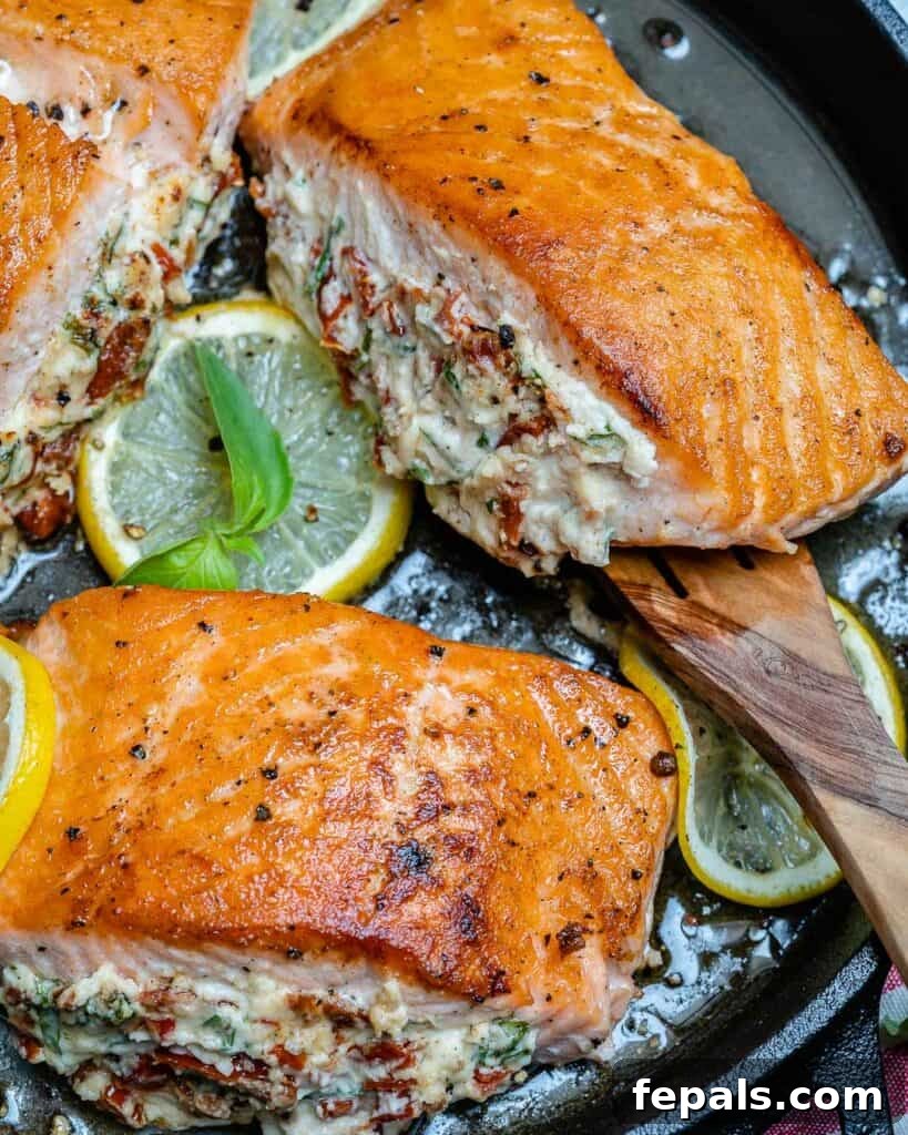 spoon grabbing a stuffed salmon from a black skillet 