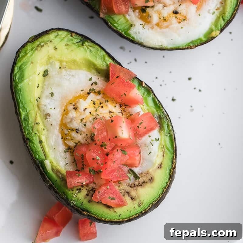 Avocado Egg Nests 2 half an avocado with a baked egg in it topped with chopped tomatoes.