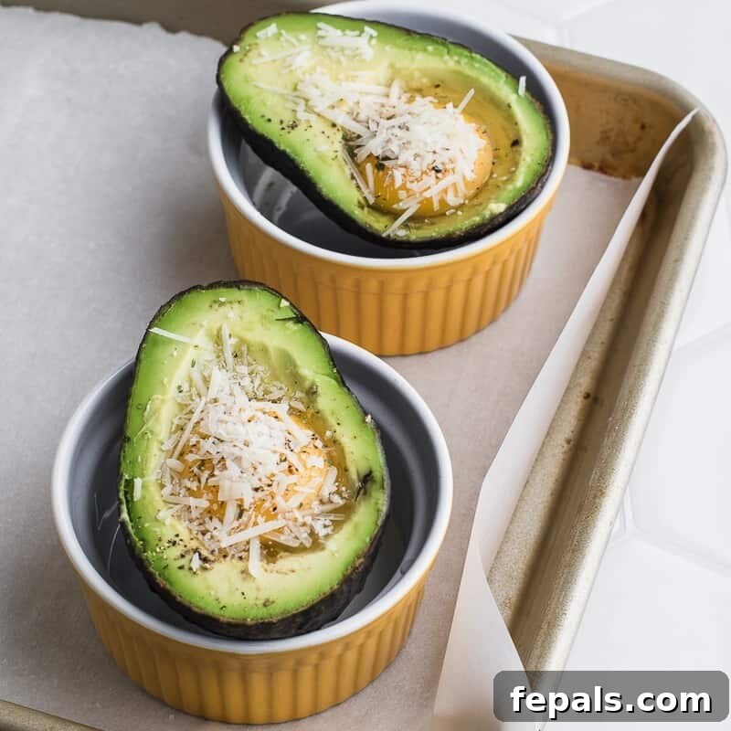 Avocado Egg Nests 3 two avocado halves in ramekins with raw egg in them topped with shredded cheese.