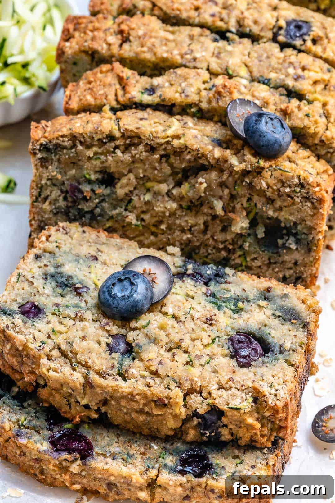 Delicious Blueberry Zucchini Bread 12 Multiple stacks of moist zucchini bread slices, adorned with fresh blueberries on top, arranged artfully.