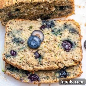Two slices of blueberry zucchini bread stacked over each other, highlighting the moist texture and blueberry distribution.