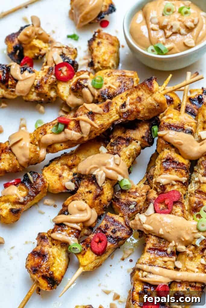 side shot of chicken skewers with peanut dipping sauce