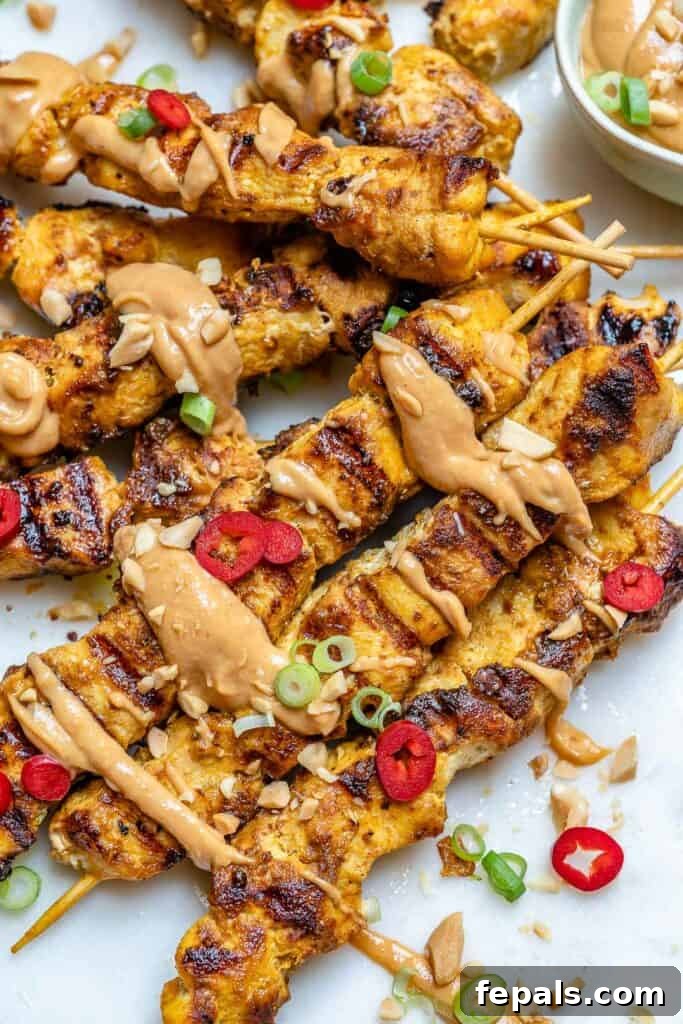 close up view of grilled chicken satay with peanut sauce drizzle 