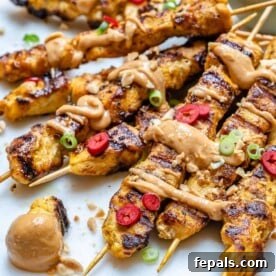 side shot of chicken satay skewers with peanut sauce