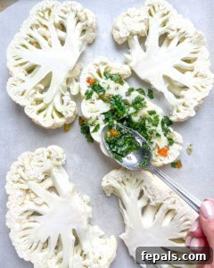 Chargrilled Cauliflower Steaks with Fresh Chimichurri 14 hand with a spoon adding chimichurri sauce over cauliflower steaks.