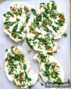 Chargrilled Cauliflower Steaks with Fresh Chimichurri 15 chimichurri sauce added over cauliflower steaks on a pan.