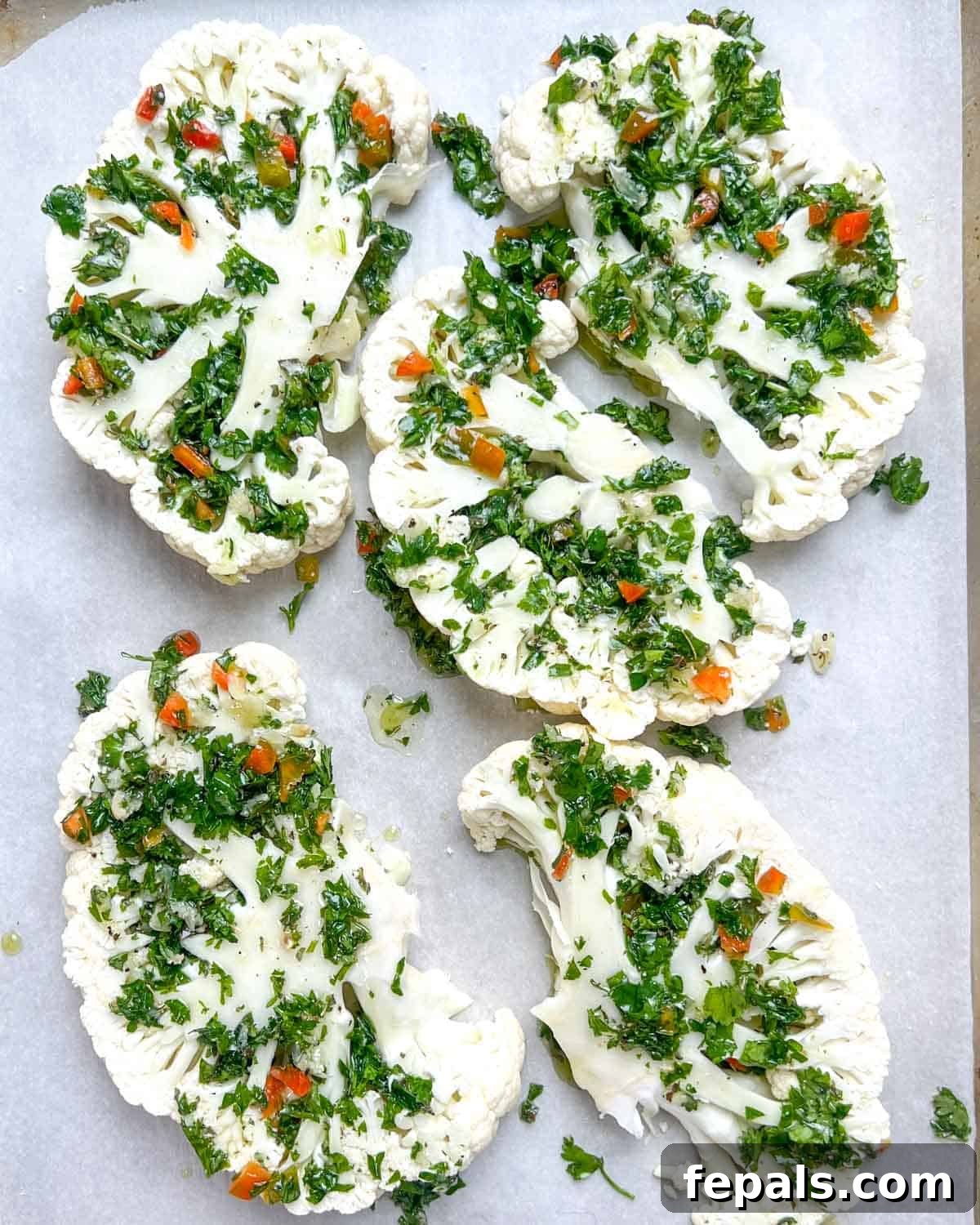 Chargrilled Cauliflower Steaks with Fresh Chimichurri 8 Cauliflower steaks beautifully brushed with chimichurri sauce, laid out on a pan, ready for grilling or roasting.