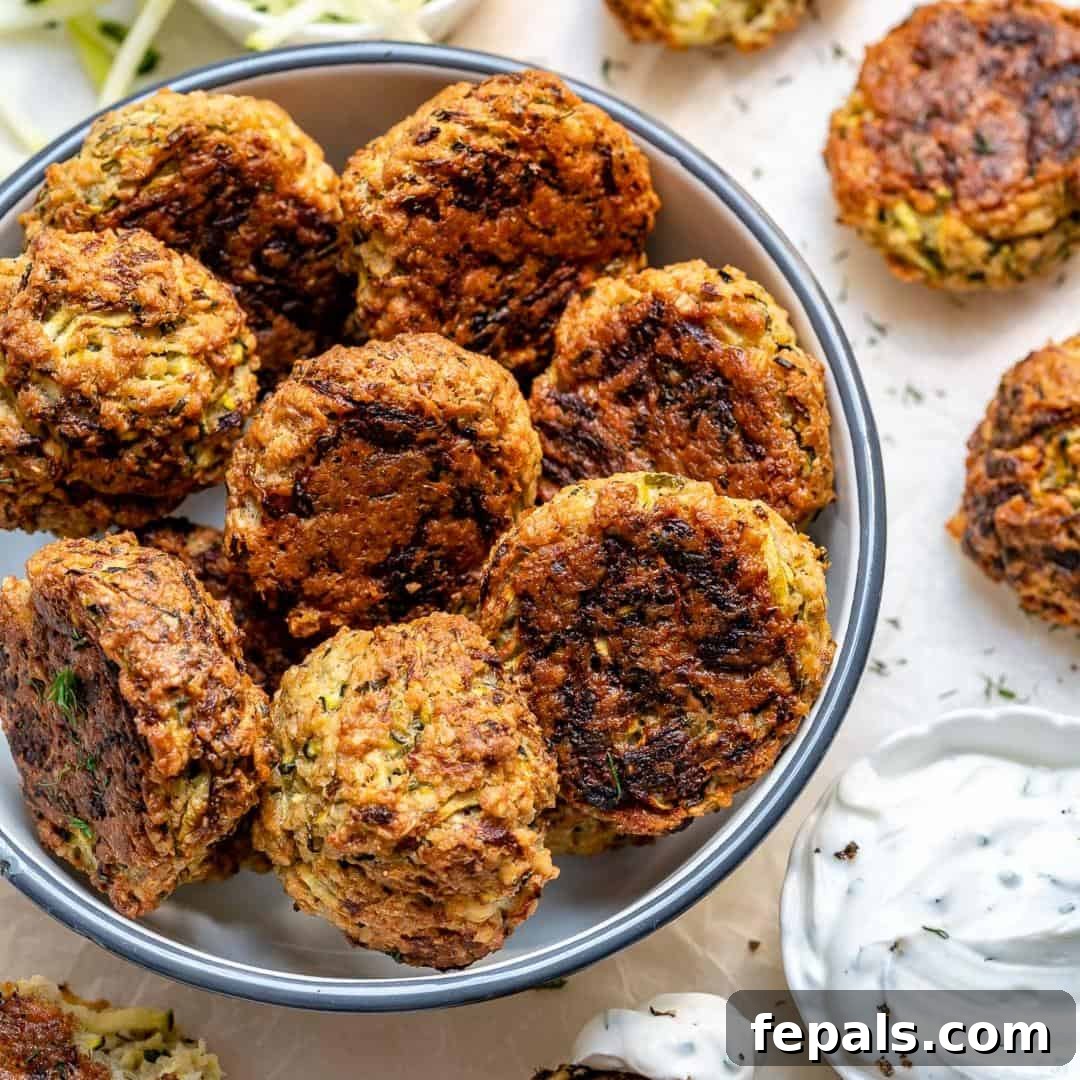 Savory Baked Garlic Herb Zucchini Fritters 6 overhead shot of a plate of baked zucchini fritters with a side of dipping sauce