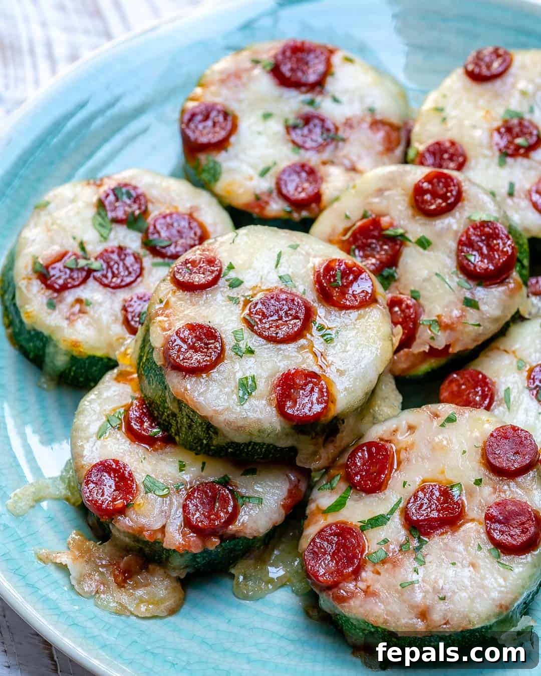 Zucchini Pizza Poppers 2 zucchini pizza bites slices topped with melted cheese and mini pepperoni, presented beautifully.