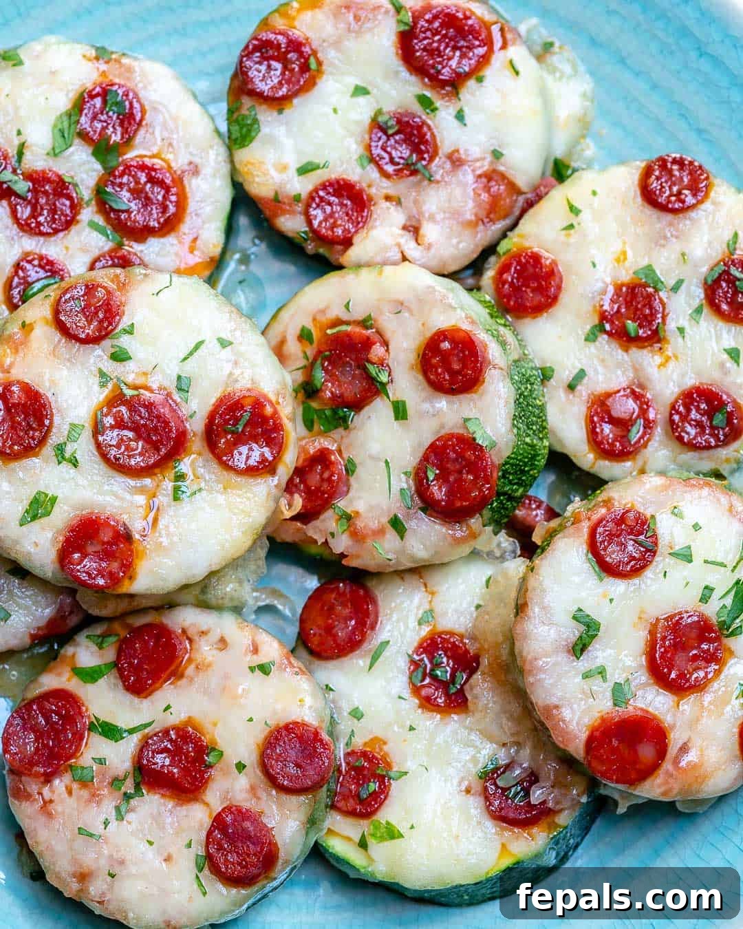 Zucchini Pizza Poppers 5 mini zucchini pizza bite slices neatly arranged on a white plate.