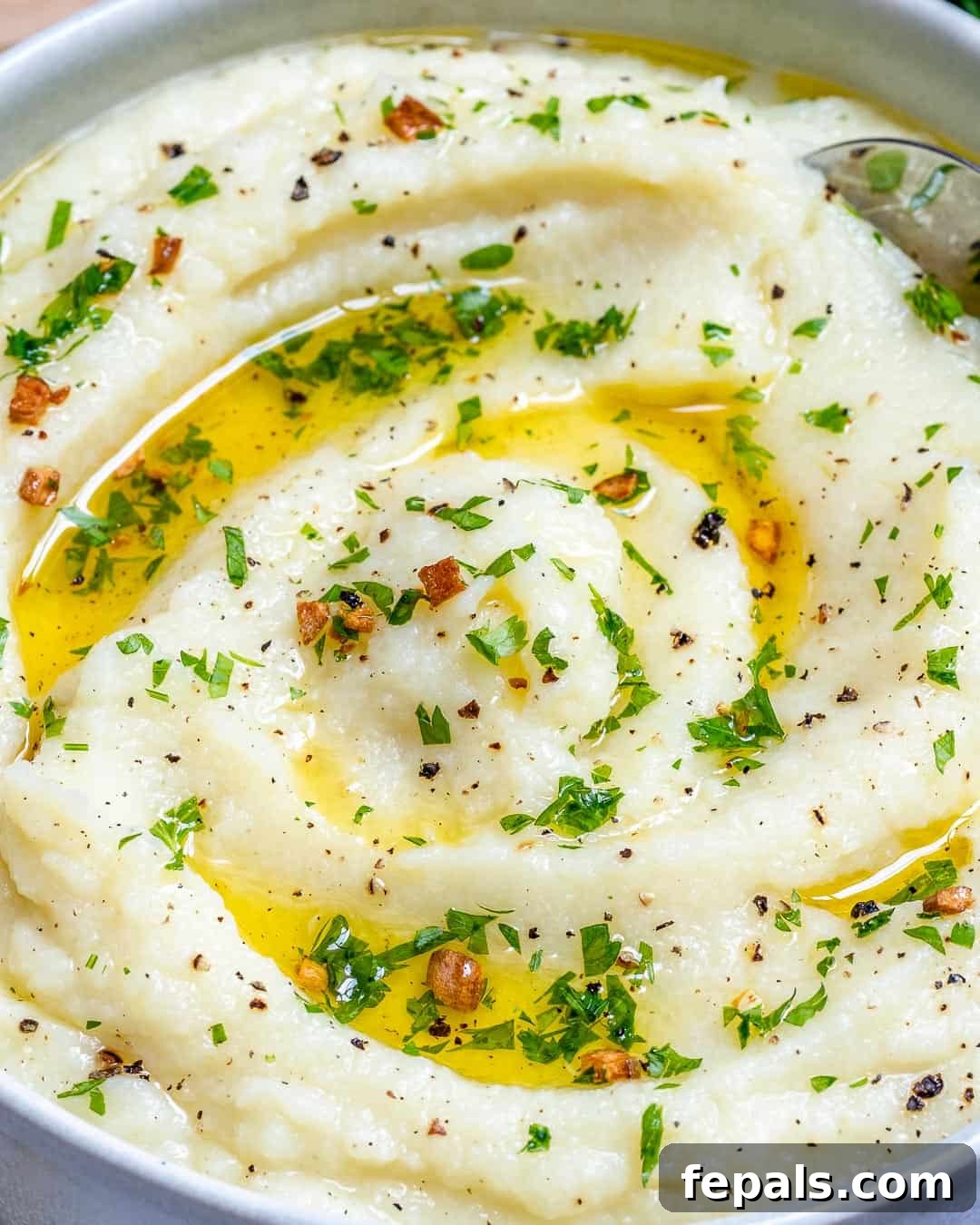 Whipped Garlic Butter Cauliflower 3 A beautifully presented bowl of mashed cauliflower, garnished with melted butter and freshly chopped garlic, highlighting its smooth and inviting texture.
