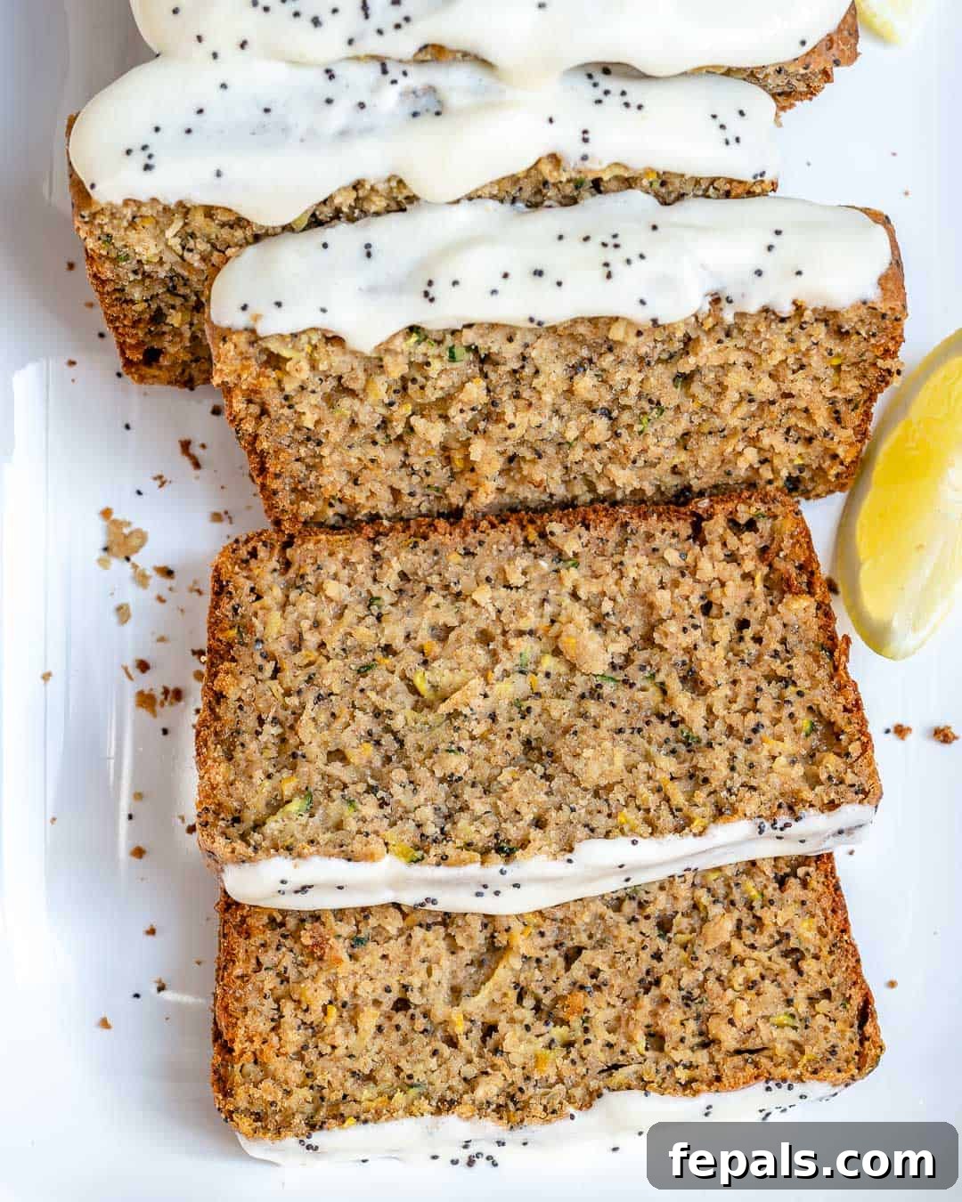 Various slices of poppy seed zucchini bread on a white serving plate, showing its moist texture.