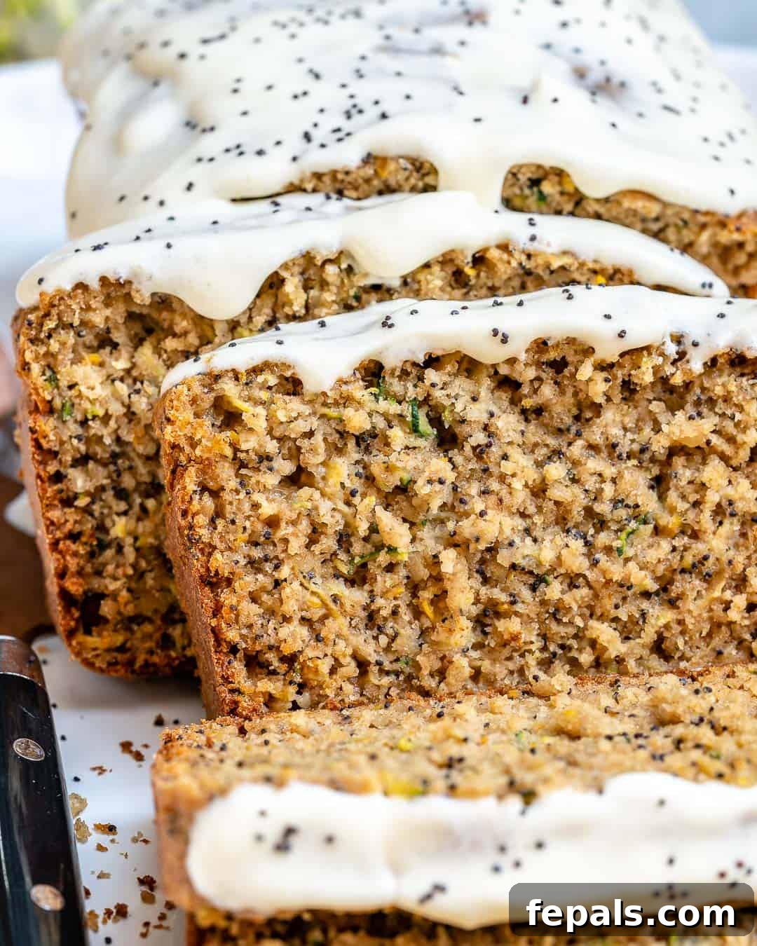 Close-up of a glazed slice of lemon poppy seed zucchini bread.