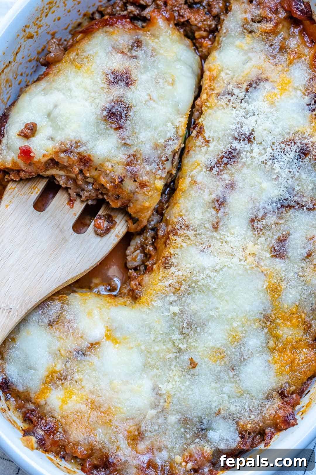 Satisfying Zucchini Lasagna Bake 2 A perfectly baked zucchini lasagna casserole, rich with melted cheese and a spatula poised to serve a generous slice. This dish showcases vibrant zucchini layers and a robust meat sauce.