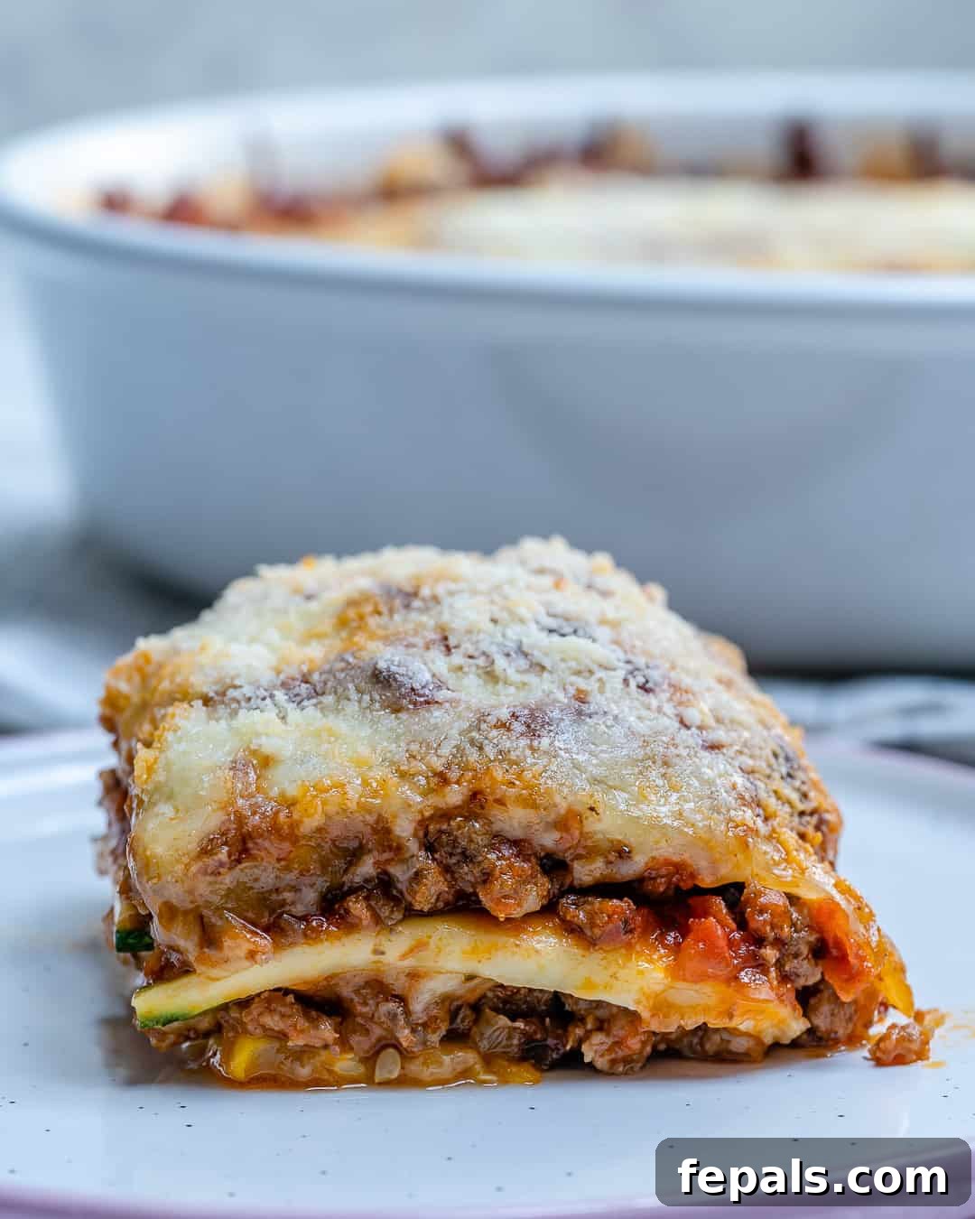 Satisfying Zucchini Lasagna Bake 11 A perfectly portioned slice of zucchini lasagna on a white plate, showcasing its distinct layers and appealing golden-brown cheese topping.