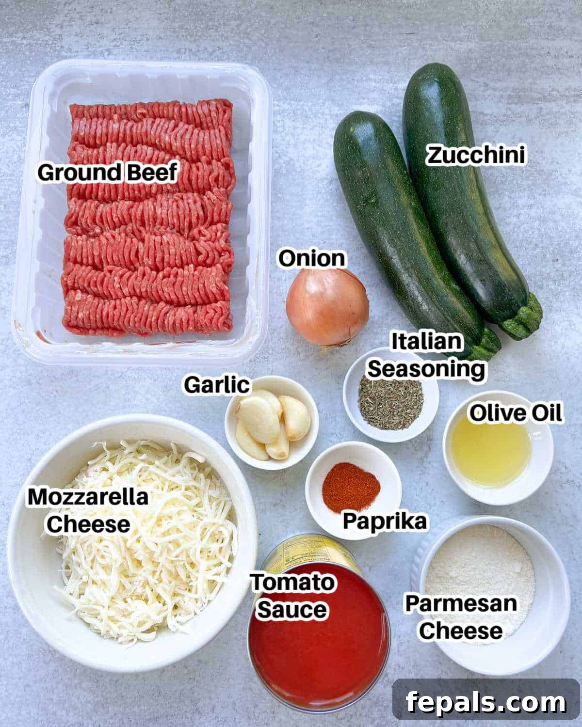 Satisfying Zucchini Lasagna Bake 3 A vibrant display of fresh ingredients laid out on a kitchen counter, including whole zucchinis, a bowl of lean ground beef, sweet onions, garlic, tomato sauce, and various cheeses, ready for making zucchini lasagna.
