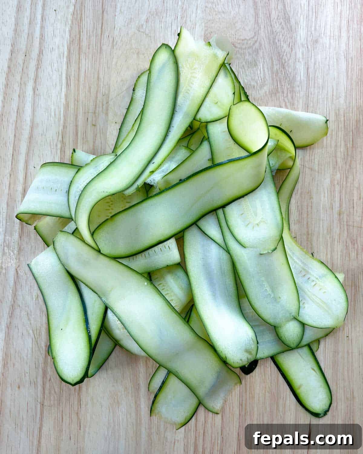 Satisfying Zucchini Lasagna Bake 4 Thinly sliced zucchini arranged on a cutting board, ready for layering. The slices are uniform and consistent in thickness.