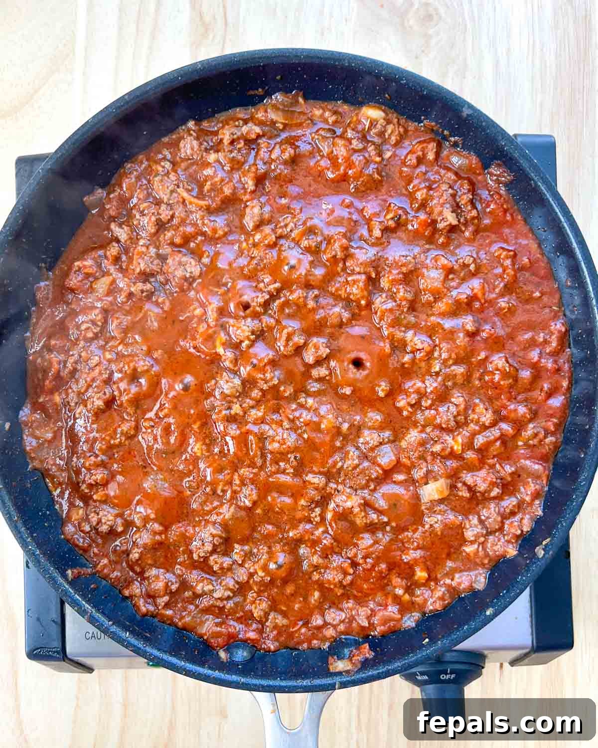 Satisfying Zucchini Lasagna Bake 5 A close-up shot of rich, savory ground beef simmering in a vibrant tomato sauce within a large nonstick pan, creating the hearty filling for the lasagna.