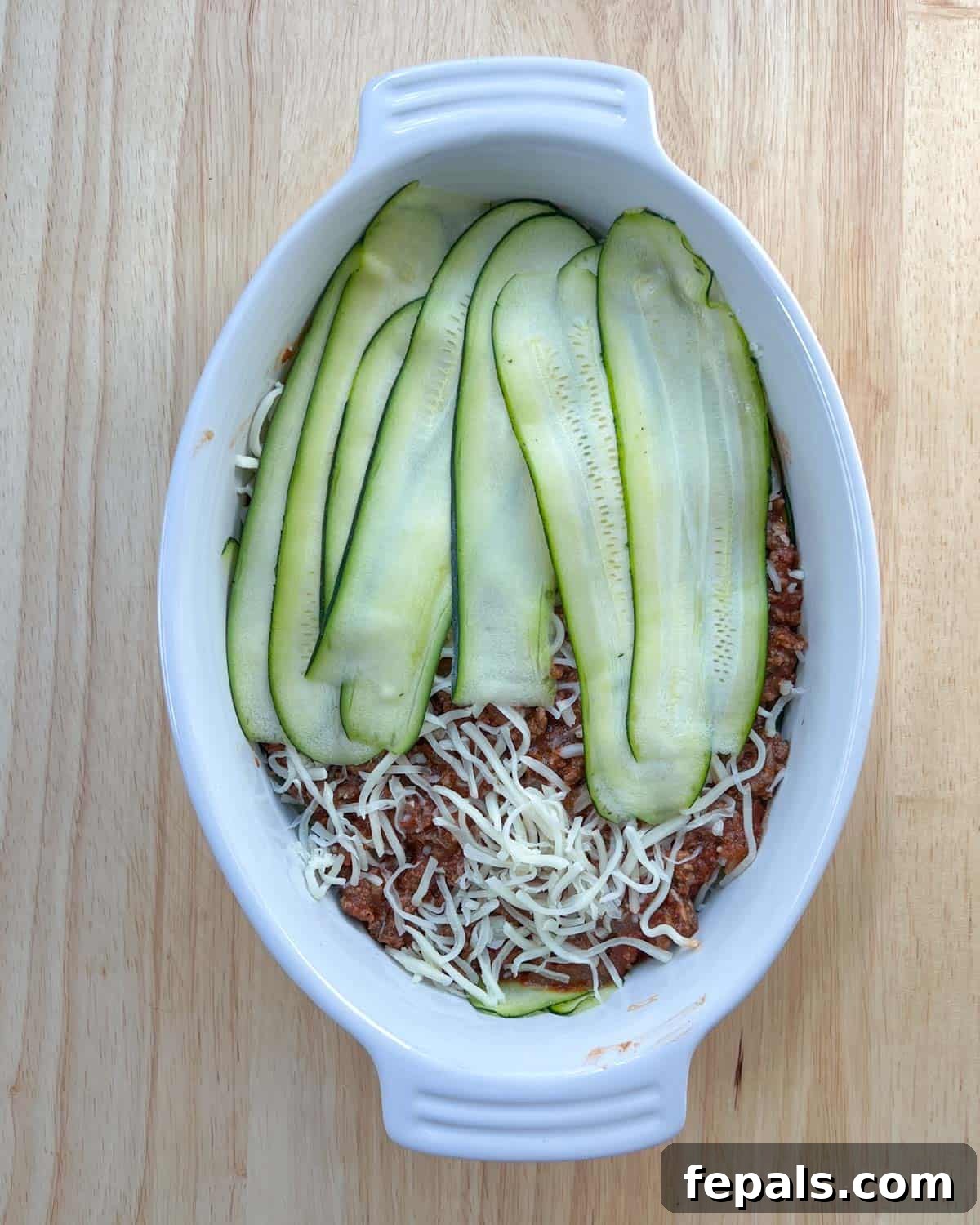 Satisfying Zucchini Lasagna Bake 8 Multiple layers of zucchini, meat sauce, and cheese building up within the baking dish, showcasing the progression of the lasagna assembly.