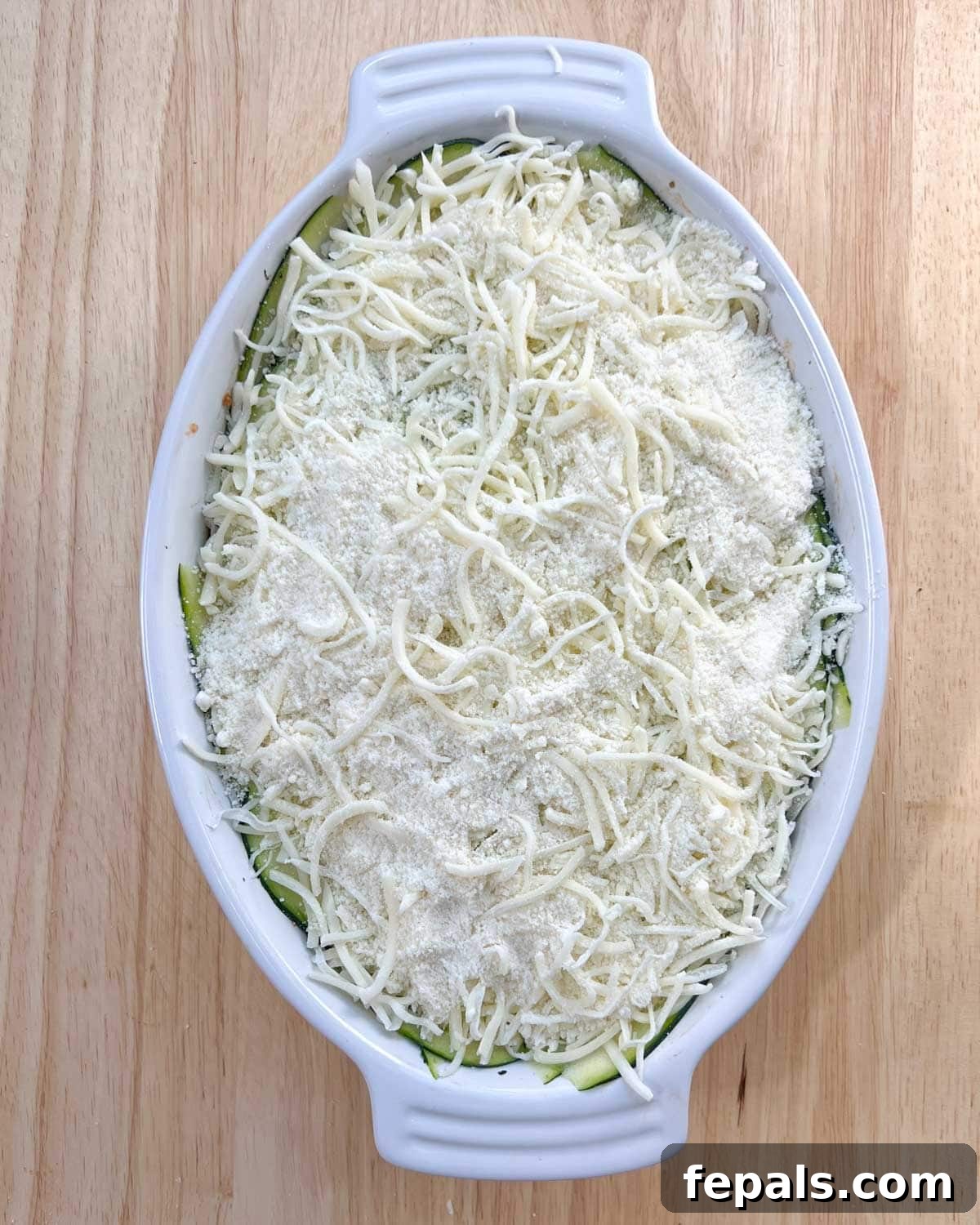 Satisfying Zucchini Lasagna Bake 9 The top layer of zucchini lasagna, richly covered with shredded mozzarella and grated Parmesan cheese, ready to be baked to golden, bubbly perfection.