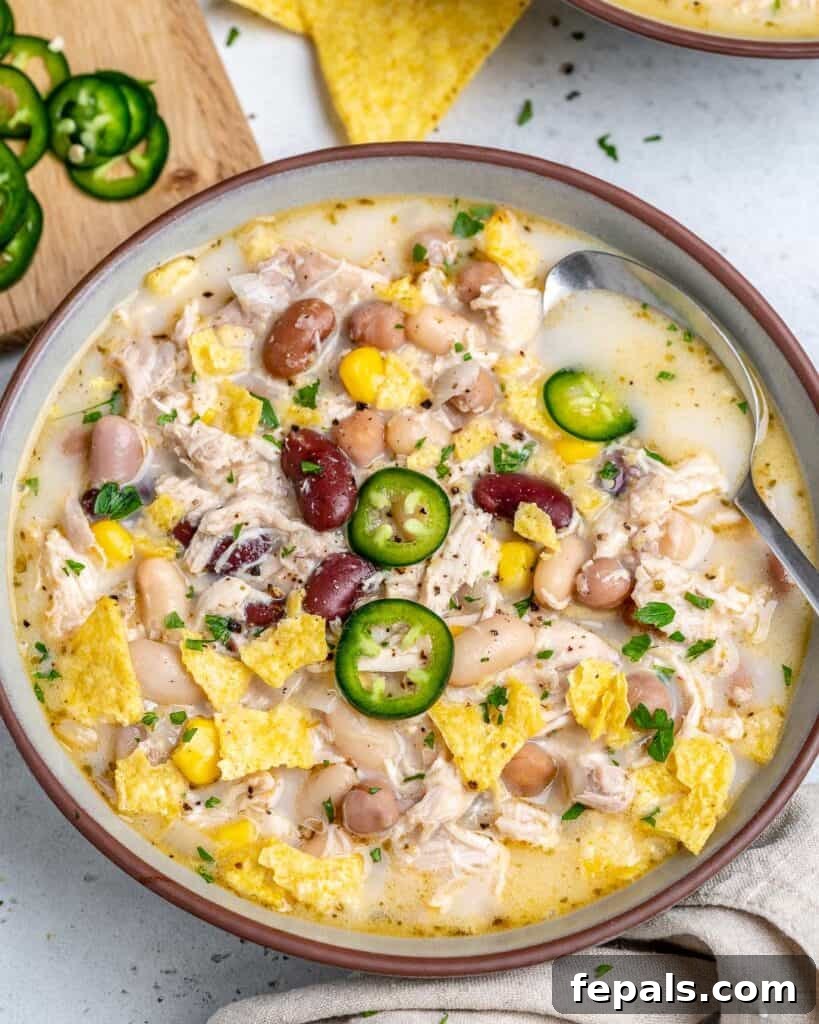 Creamy White Chicken Chili 5 round bowl of white chicken chili with beans and spoon in bowl