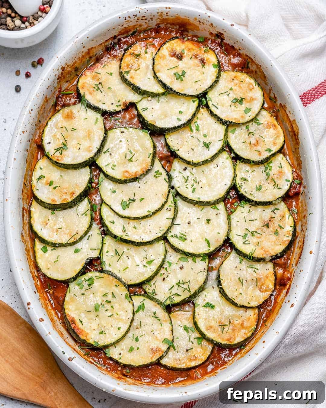Savory Greek Zucchini Moussaka 2 An oval dish of baked moussaka with layered zucchini slices, ready to be served.