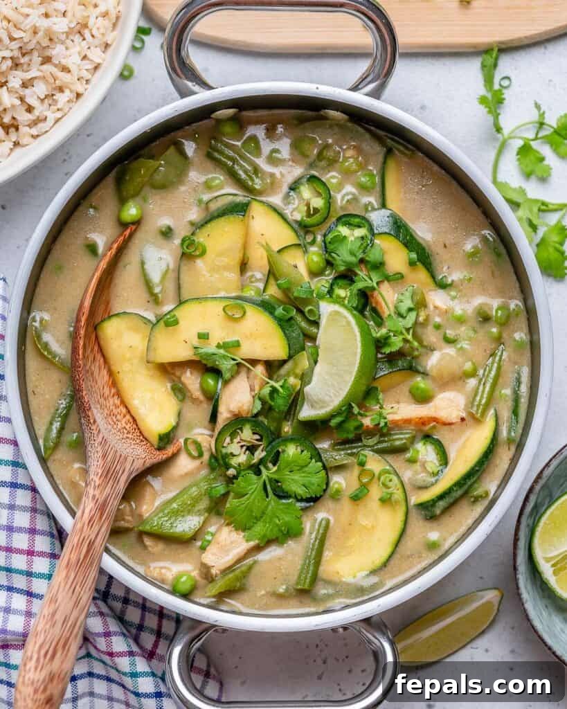 wooden spoon in a pan with mostly green Thai chicken curry