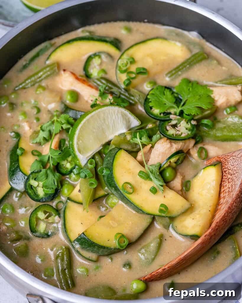 close up image of a pan with green curry recipe with green veggies topped with fresh cilnatro and sliced green onions
