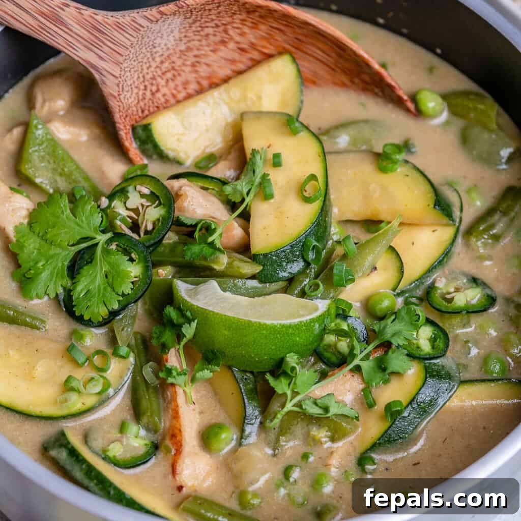 close up of a wooden spoon in green colored chicken curry recipe