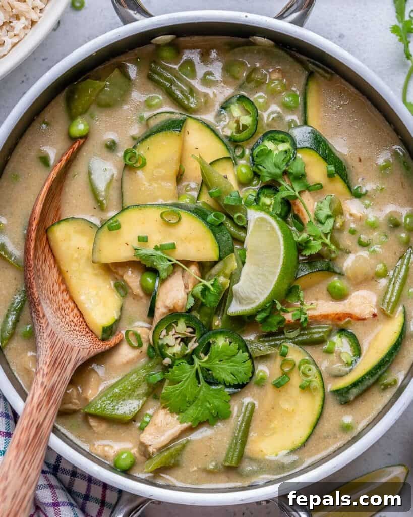wooden spoon in a pan with veggies and chicken curry recipe