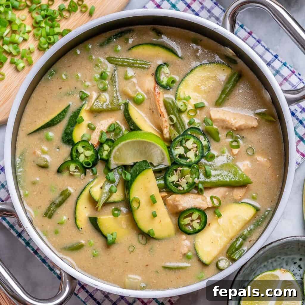 Top view of thai Green Chicken Curry in a stainless steel pan topped with green onions and fresh cilantro