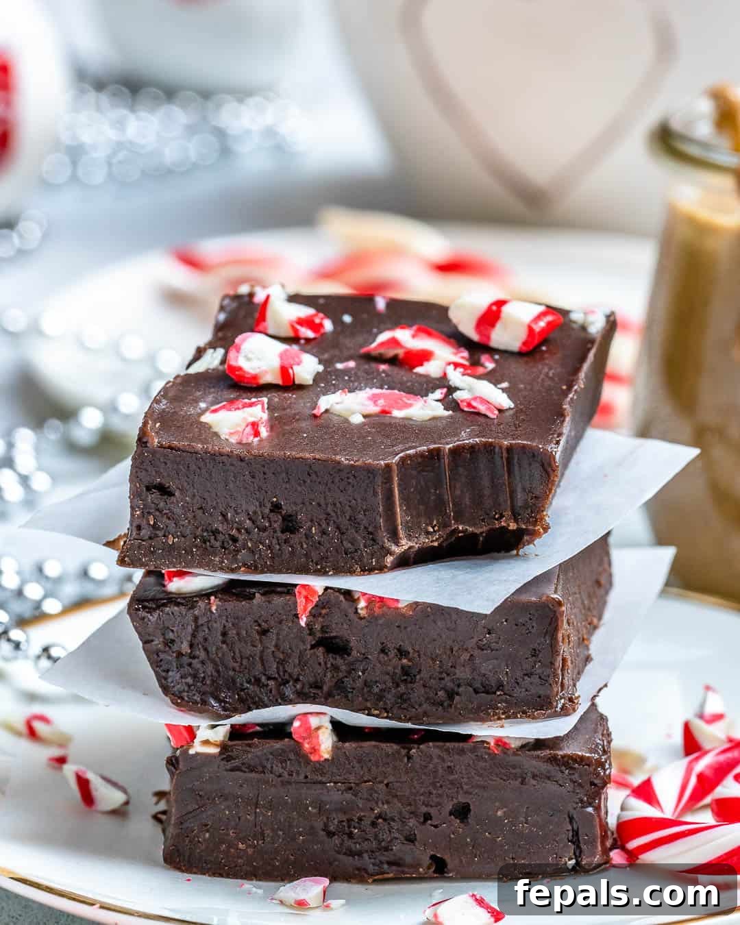 Easy and delicious homemade chocolate peanut butter peppermint fudge squares on a wooden board