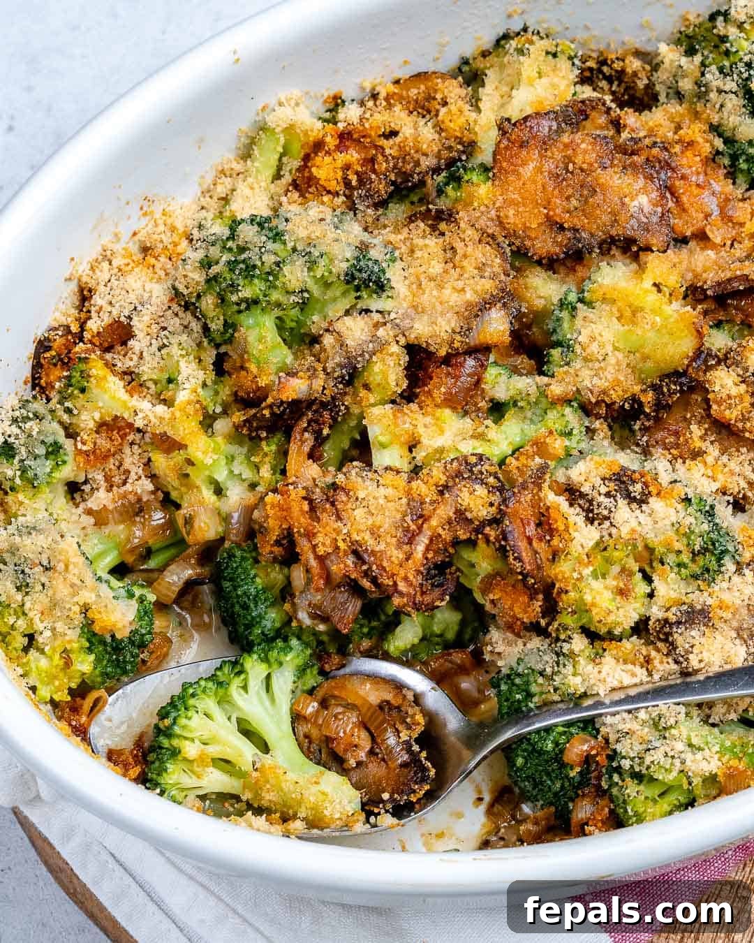 A close-up shot of a spoon in a dish, showing a generous serving of healthy broccoli and mushroom casserole, ready to be enjoyed.