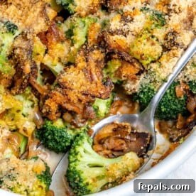 A spoonful of healthy broccoli casserole with mushroom in a white dish, highlighting its delicious texture.
